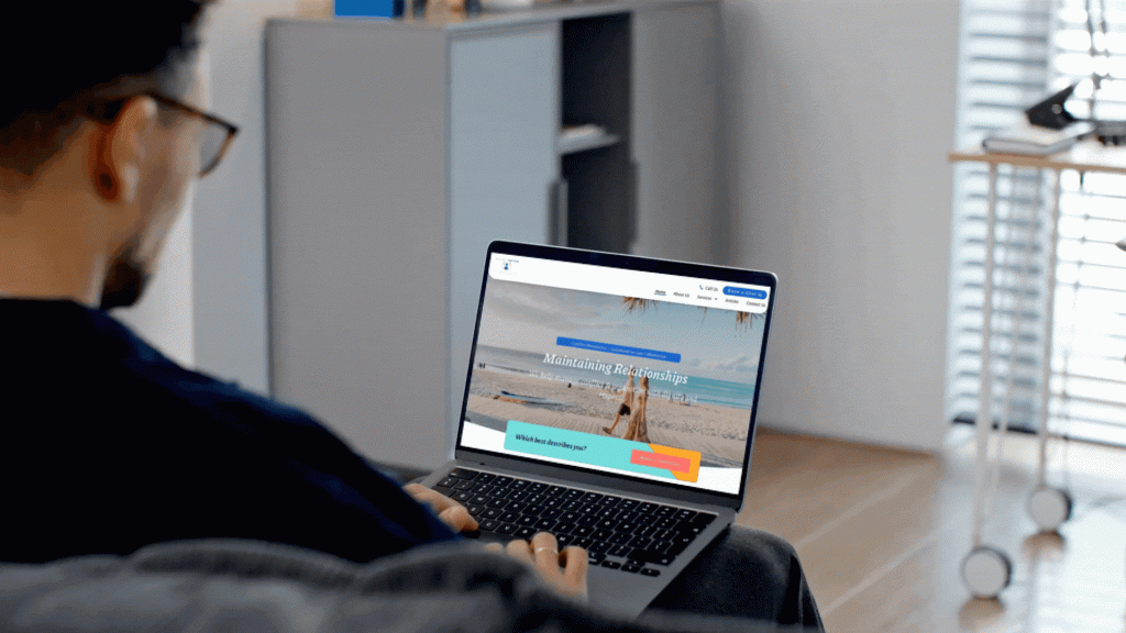 Person using a laptop to view a website showcasing a beach scene, illustrating web development and design services by Adonis Designs, emphasizing brand storytelling and user engagement.