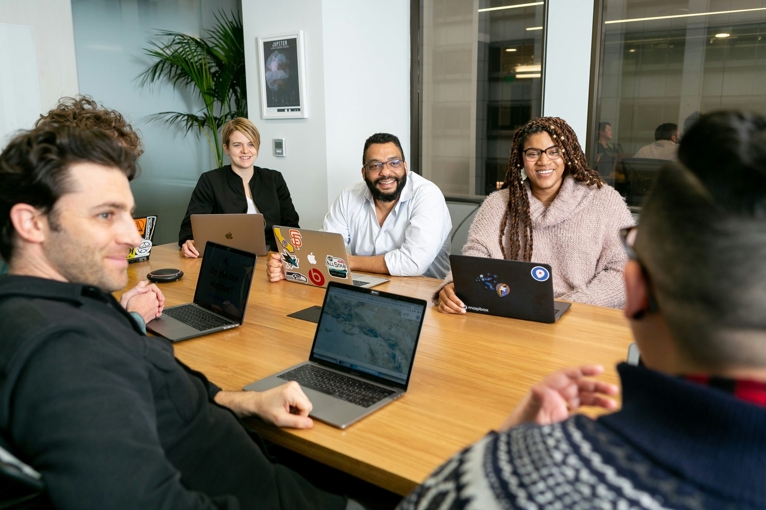 Team collaborating in a modern office, engaged in discussion with laptops, showcasing creative teamwork and digital solutions for business growth.