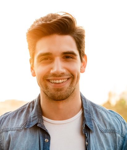Joyful unshaven man smiling outdoors, representing the passionate team at Adonis Designs, dedicated to creating impactful digital strategies and custom websites.